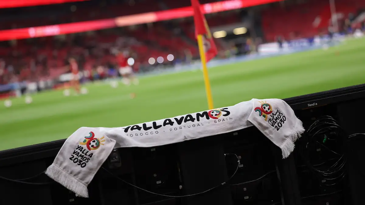 Fußball-WM 2030: Schal zeigt die Gastgeberländer Marokko, Portugal und Spanien vor einem Spielfeld