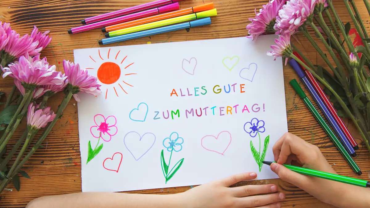 Debatte um Kindergarten: Kind malt ein Bild mit der Aufschrift „Alles Gute zum Muttertag“