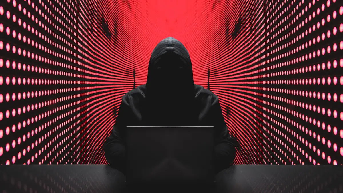 PayPal-Betrug: Kapuzengestalt sitzt an vor rotem Hintergrund an einem Laptop