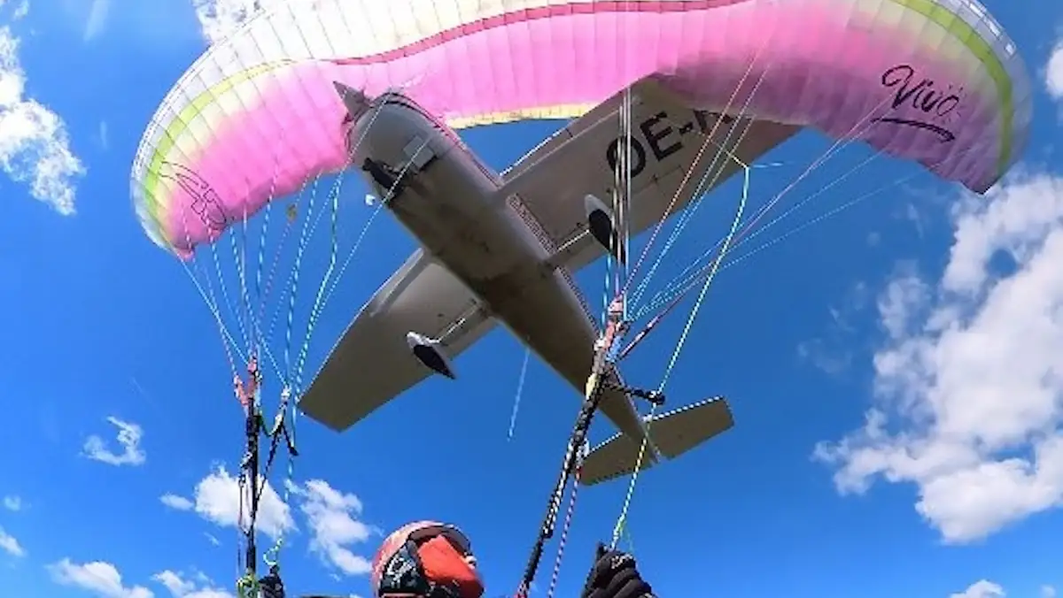 Kleines Flugzeug fliegt in den Schirm einer Paragliderin