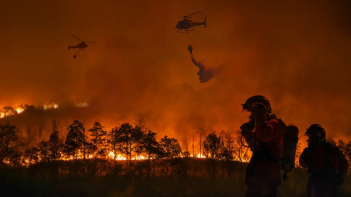 Rettungskräfte und Hubschrauber versuchen, einen Waldbrand zu löschen