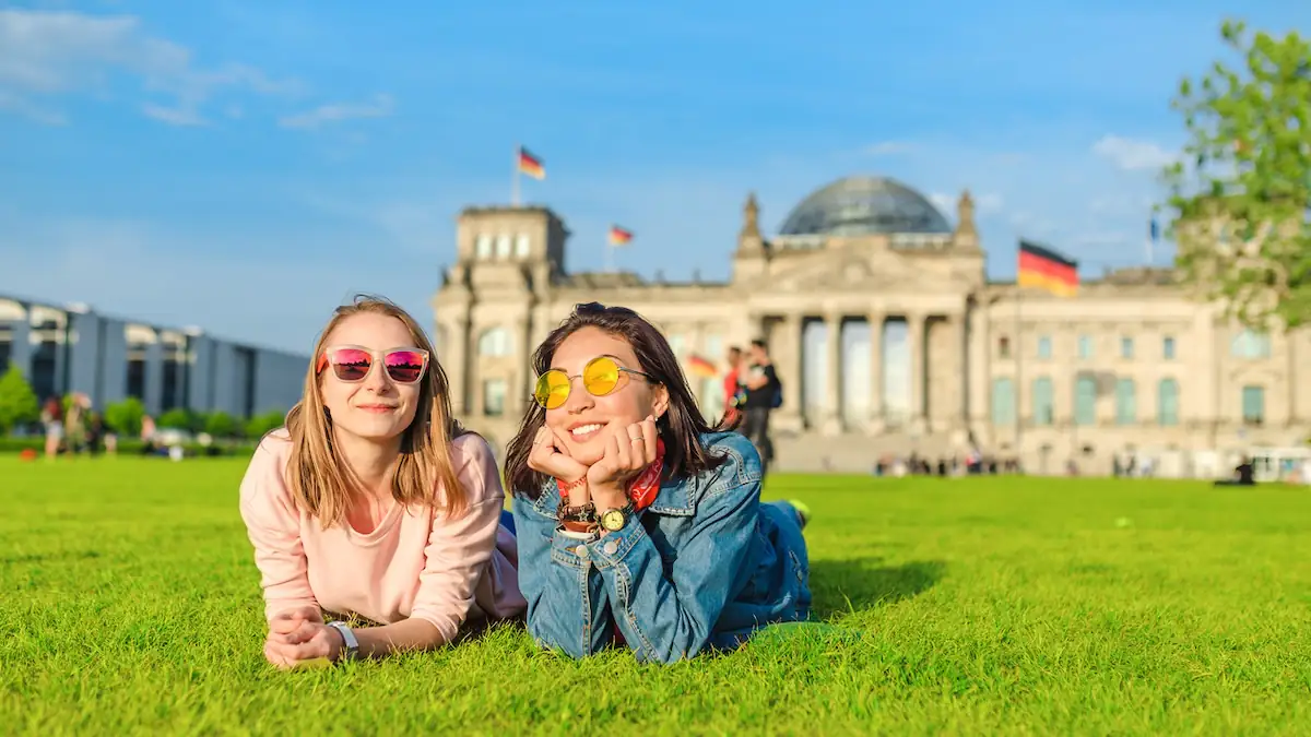 Wetterumschwung Deutschland: Zwei jungen Frauen liegen zusammen bei Sommerwetter auf der Wiese vor dem deutschen Bundestag