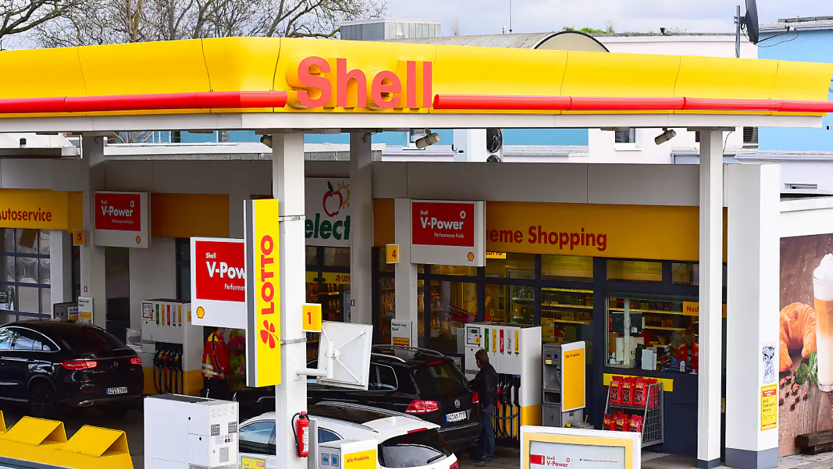 Eine Shell-Tankstelle mit dem Logo und einem weißen Auto an der Zapfsäule