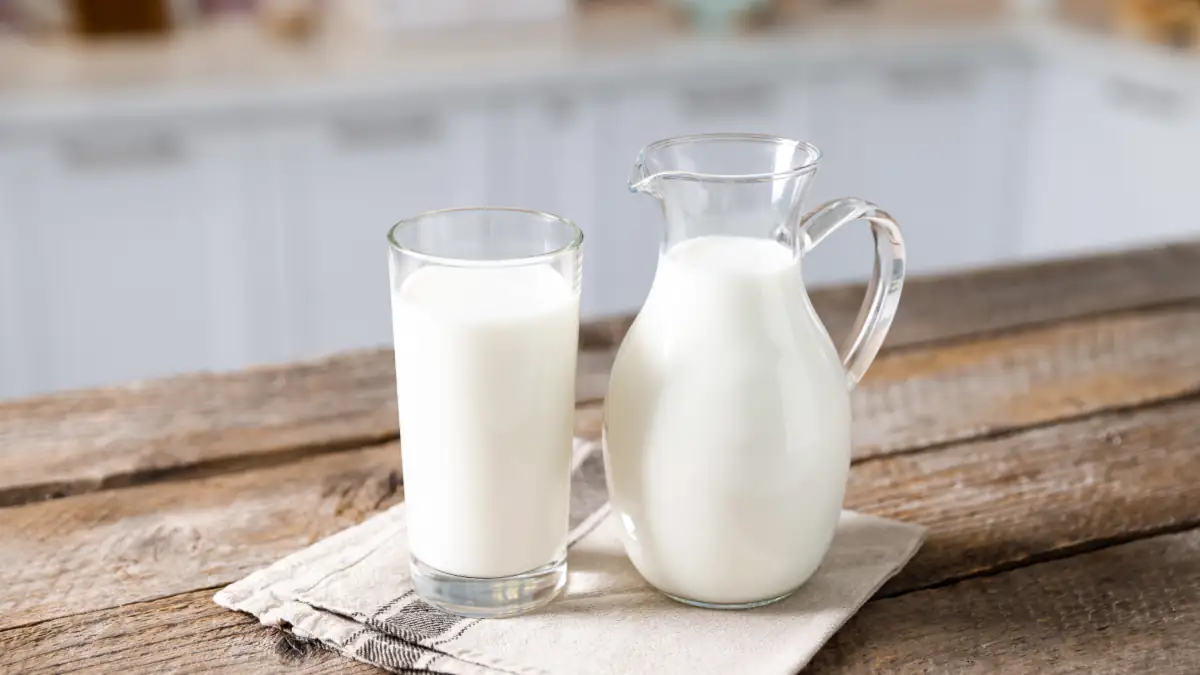Ein Glas Milch neben einem Krug