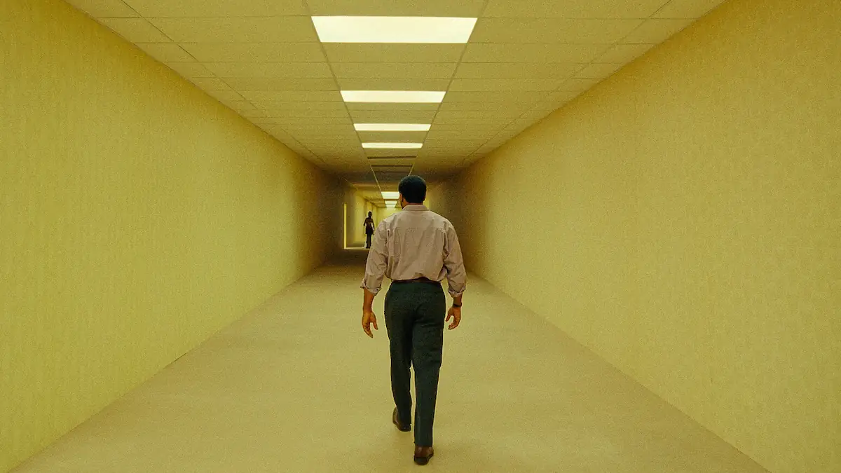 Szene aus dem Horrorfilm „Backrooms“, in der ein Mann einen gelben Gang hinuntergeht
