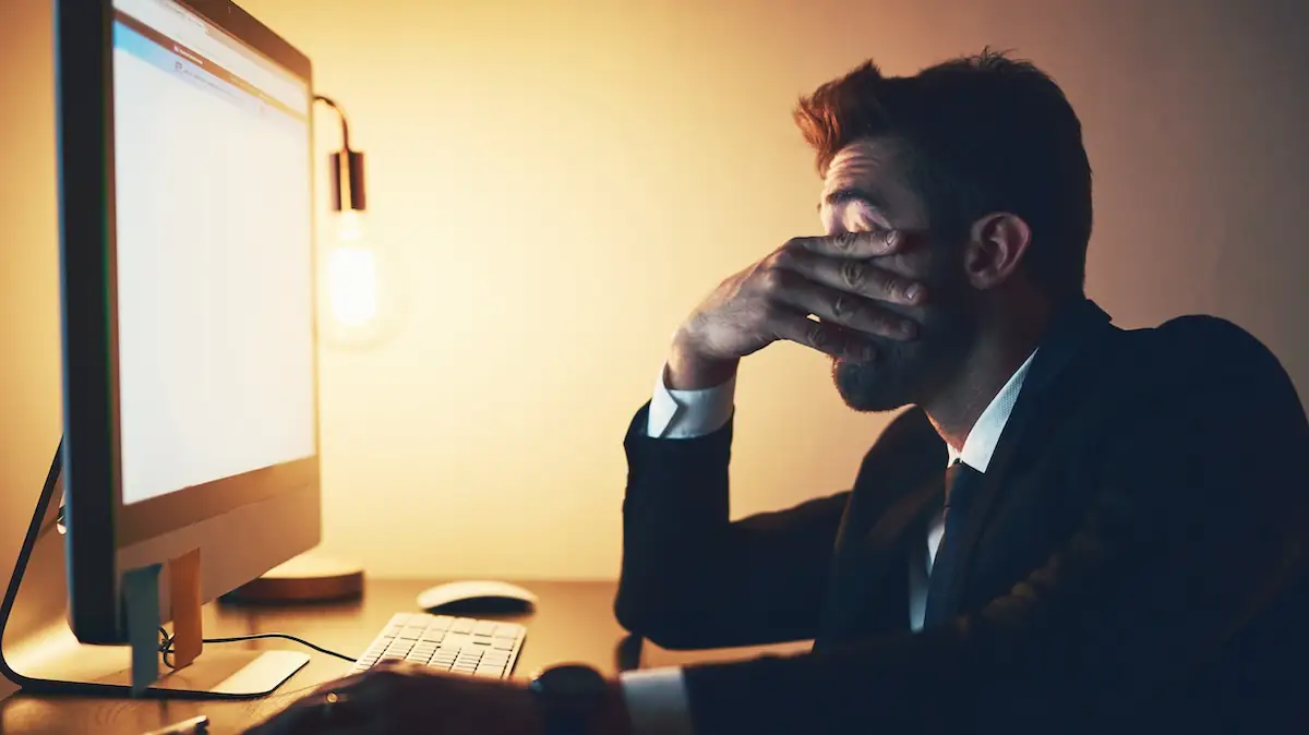 Burnout: Müder Business-Mann sitzt abends am Laptop