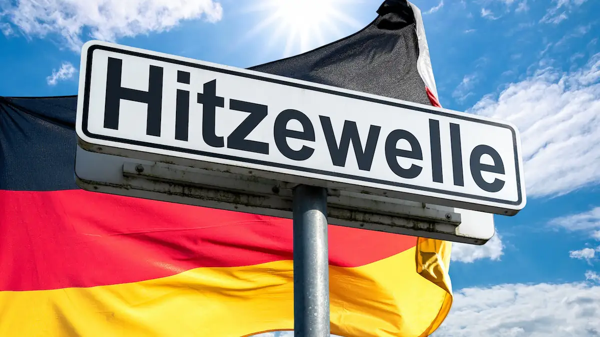 Schild mit der Aufschrift „Hitzewelle“ vor einer Deutschland-Flagge