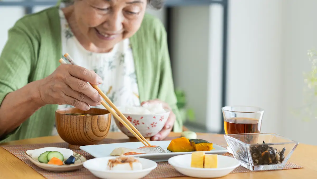 Japanische Frau isst traditionelles Essen mit Stäbchen