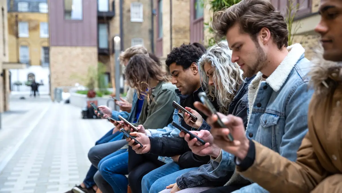 Social Media: Eine Gruppe junger Leute sitzt beisammen, alle sind mit ihren Smartphones beschäftigt