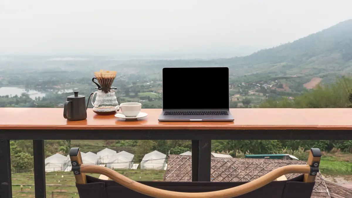 Workation: Laptop neben Kaffeetasse vor schöner Aussicht