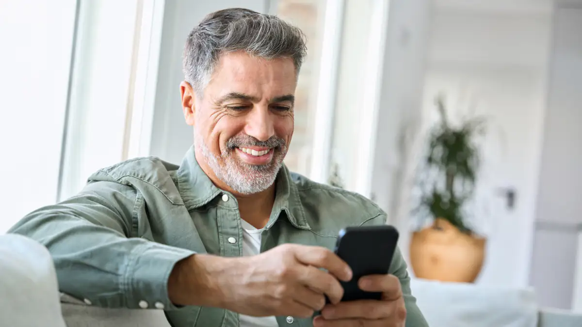 Placeholder-Partner: Mann schaut lächelnd auf sein Smartphone