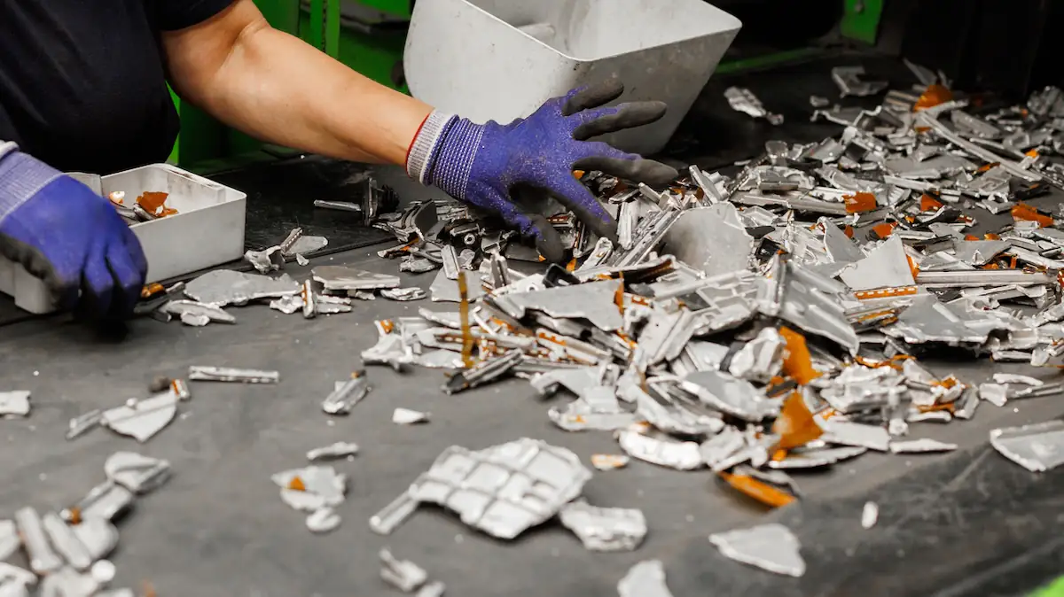 Lithium-Ionen-Akkus im Recycling-Prozess in ihren Einzelteilen, die von einer Person sortiert werden