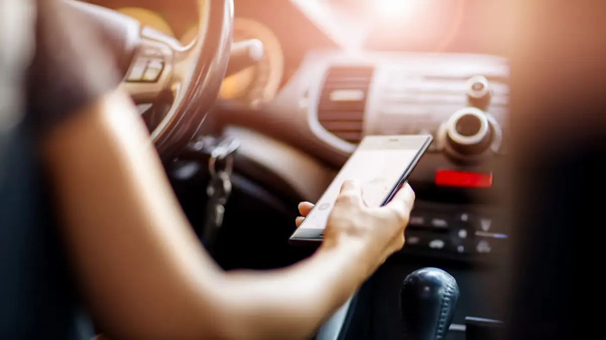 Autofahrerin schaut auf ihr Smartphone