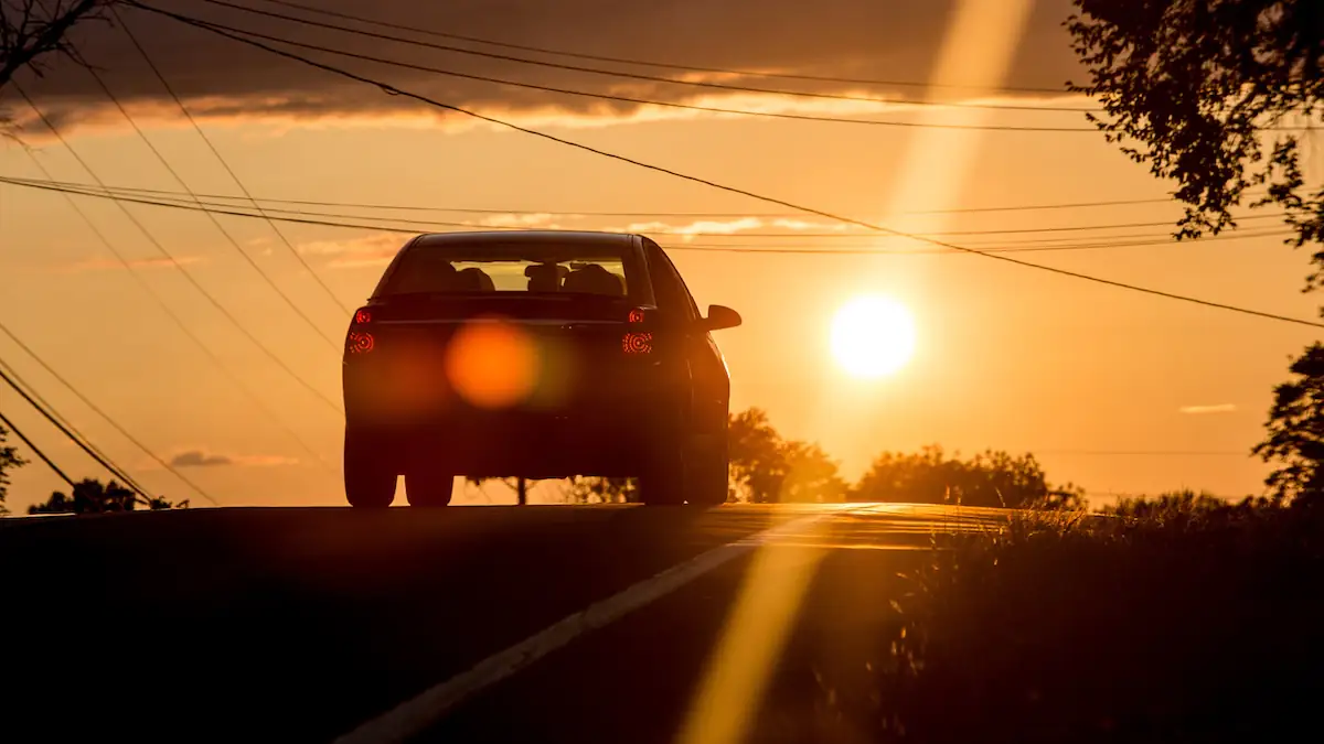 Auto bei Hitze fährt auf einer Straße Richtung Sonne
