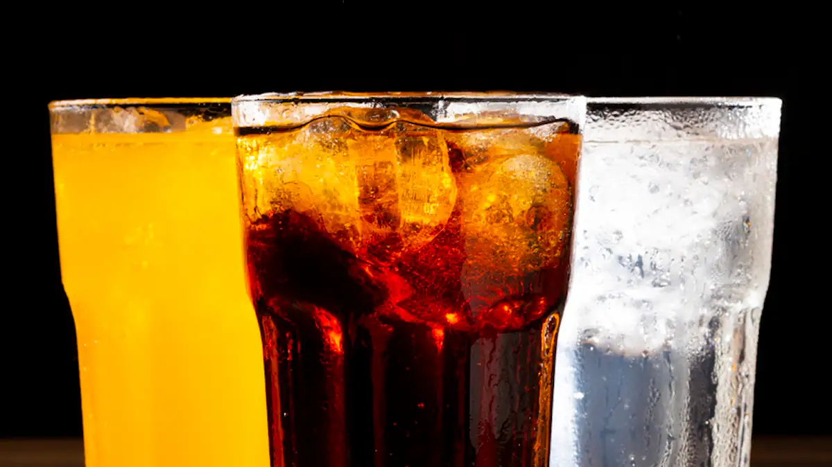 Fanta, Cola und Sprite jeweils in einem Glas vor schwarzem Hintergrund