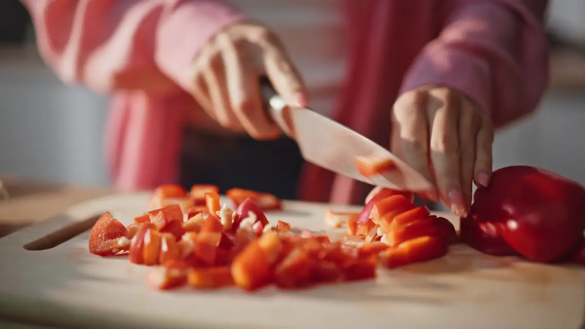 Lebensmittel gegen Hautalterung: Nahaufnahme, wie rote Paprika auf einem Brett geschnitten wird