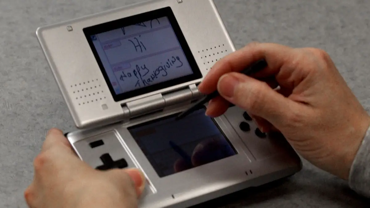 Aufgeklappter Nintendo DS in Silber, den jemand benutzt
