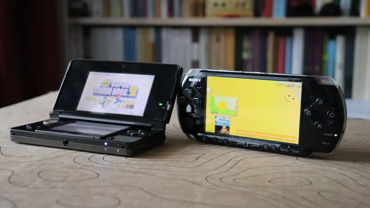 Ein aufgeklappter Nintendo DS neben einer PlayStation Portable (PSP)