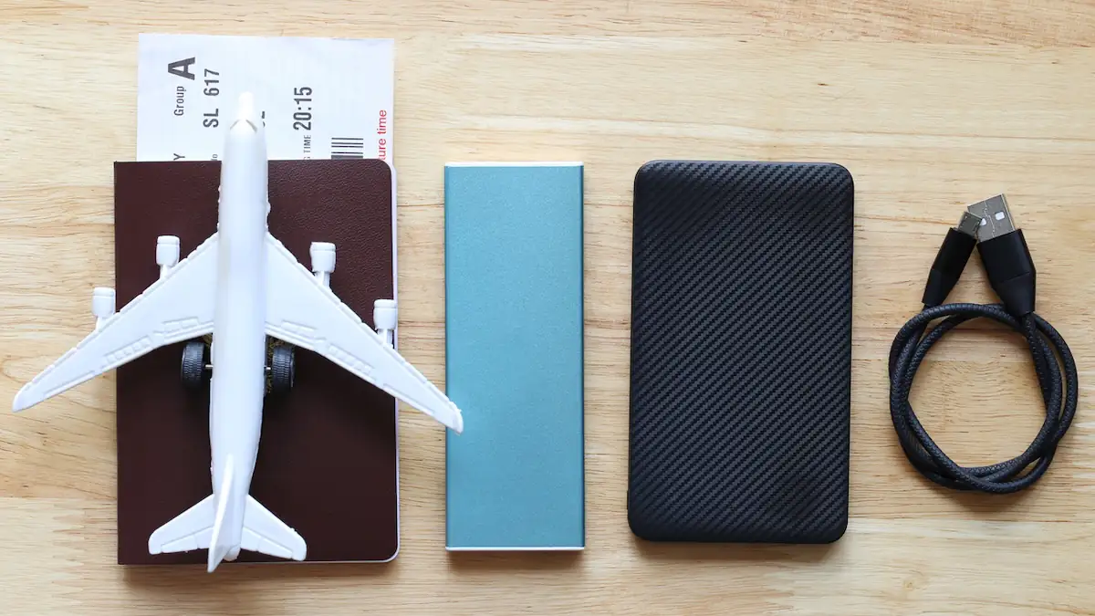 Zwei Powerbanks liegen neben einem Reisepass und einem Ladekabel