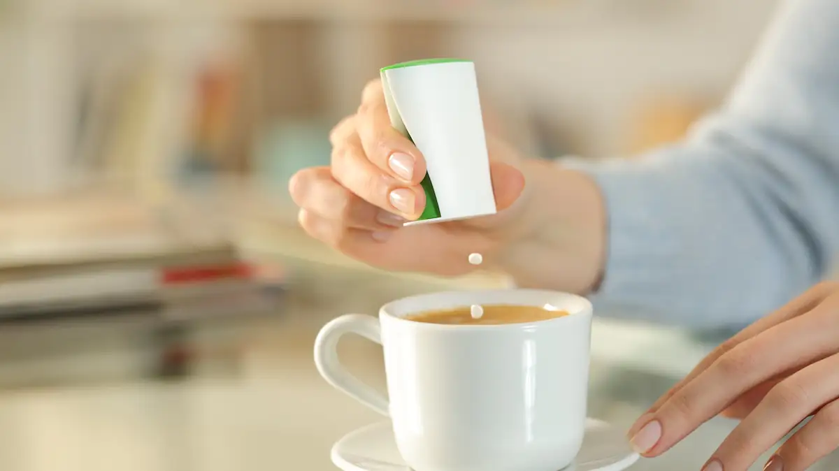 Frau gibt Süßstoff-Tabletten in ihren Kaffee