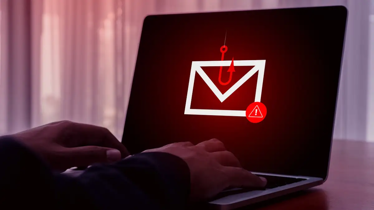Phishing bei Urlaubsbuchung: Auf einem Laptop ist ein E-Mail-Symbol mit einem Angelhaken zu sehen