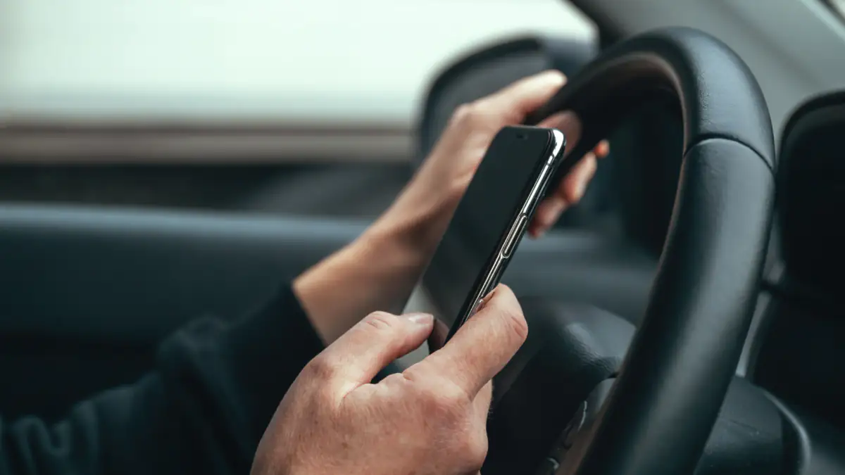 Arbeitszeit Symbolbild: Person hält Smartphone im Auto