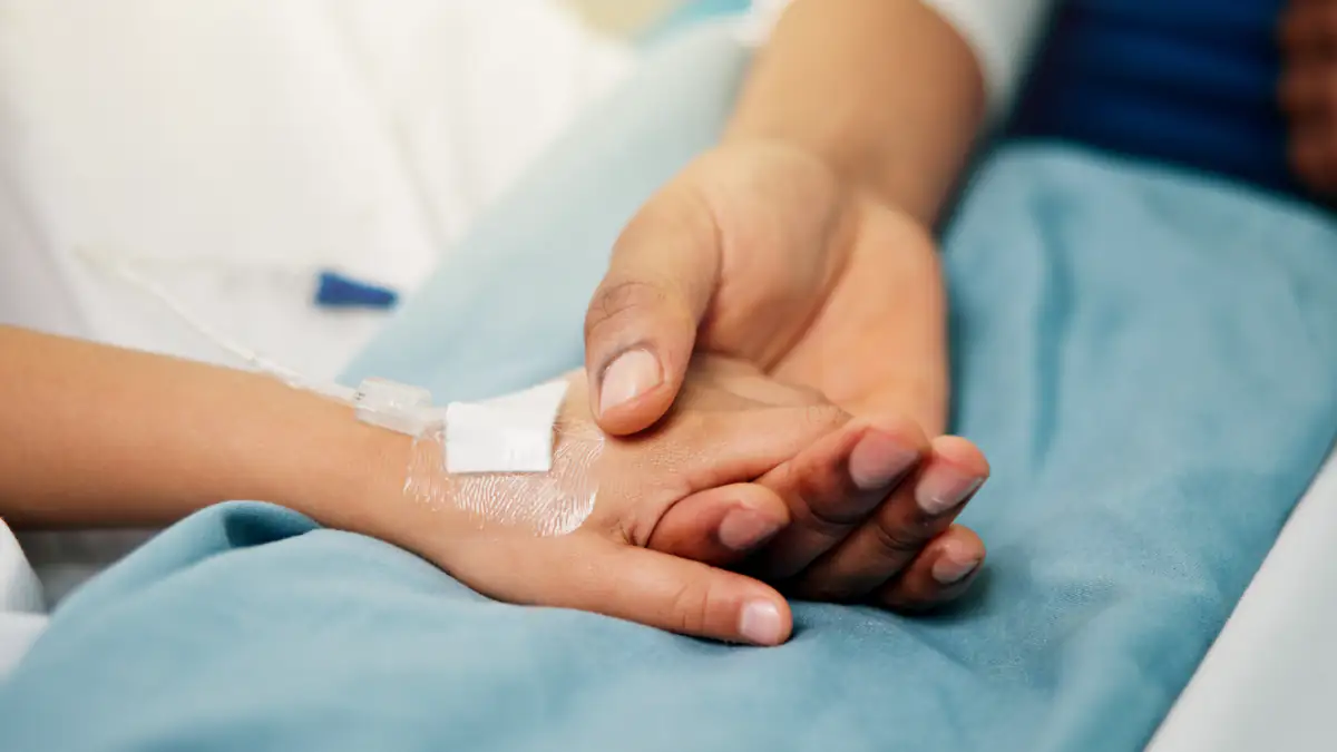 Symbolbild Benadryl-Challenge: Mutter hält Kinderhand im Krankenhaus
