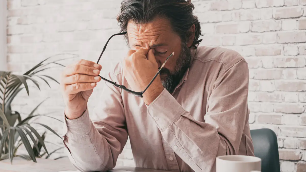 Symbolbild Gewalt gegen Männer: Mann sitzt verzweifelt an einem Tisch