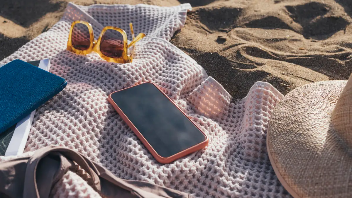 Smartphone auf einer Stranddecke im Sommer