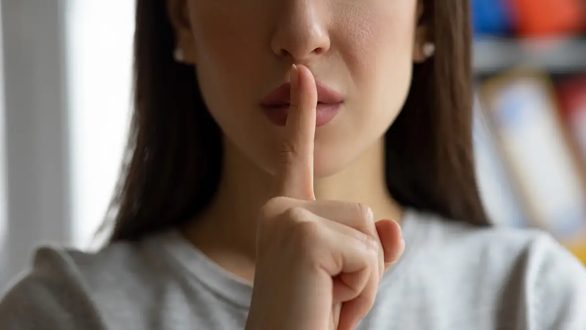 Schweigen bei Streit: Nahaufnahme einer Frau, die den Finger als „Pst“-Zeichen auf die Lippen legt
