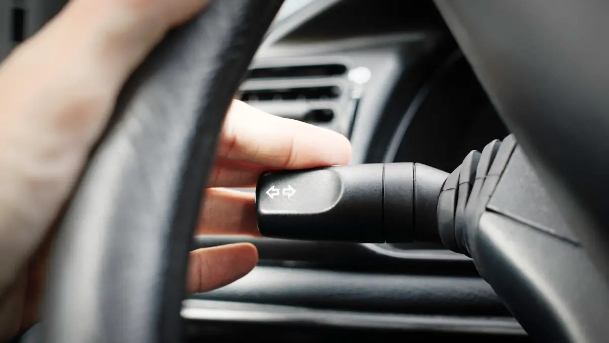 Jemand setzt zum Blinken den Blinker eines Autos