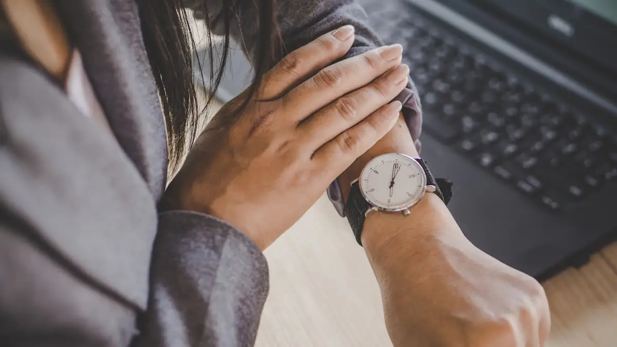 Teilzeitarbeit Symbolbild: Businessfrau schaut auf ihre Armbanduhr