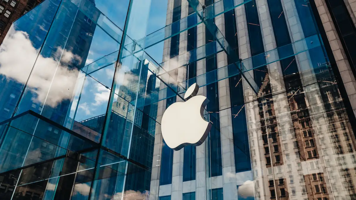 Apple Logo an einer Glasfront, in der sich der Himmel spiegelt