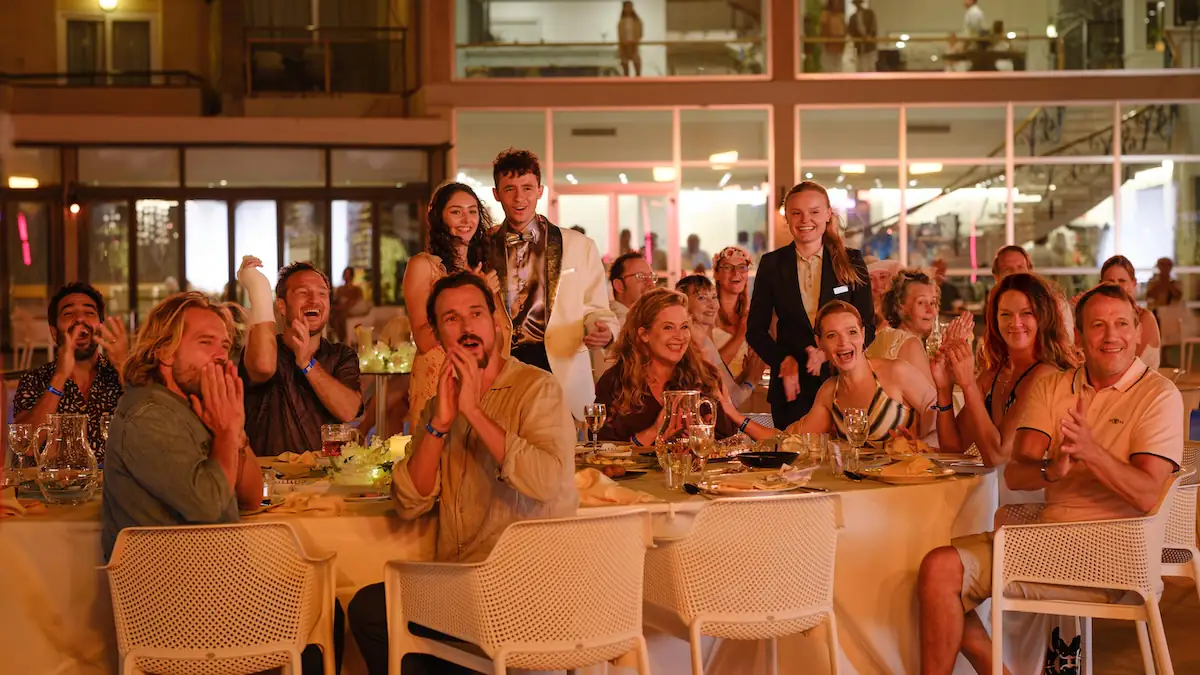 Szene aus dem Film „Der perfekte Urlaub“ zeigt Gruppe am Tisch