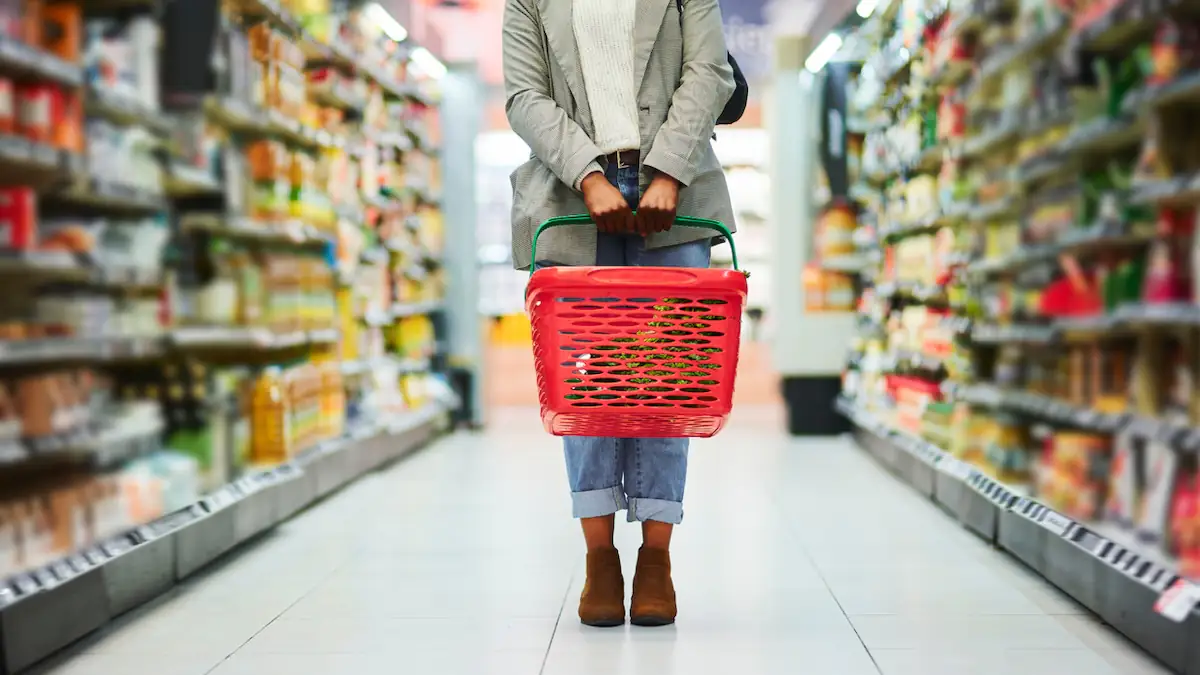 Stille Stunde: Frau steht mit Einkaufskorb in einem Supermarkt